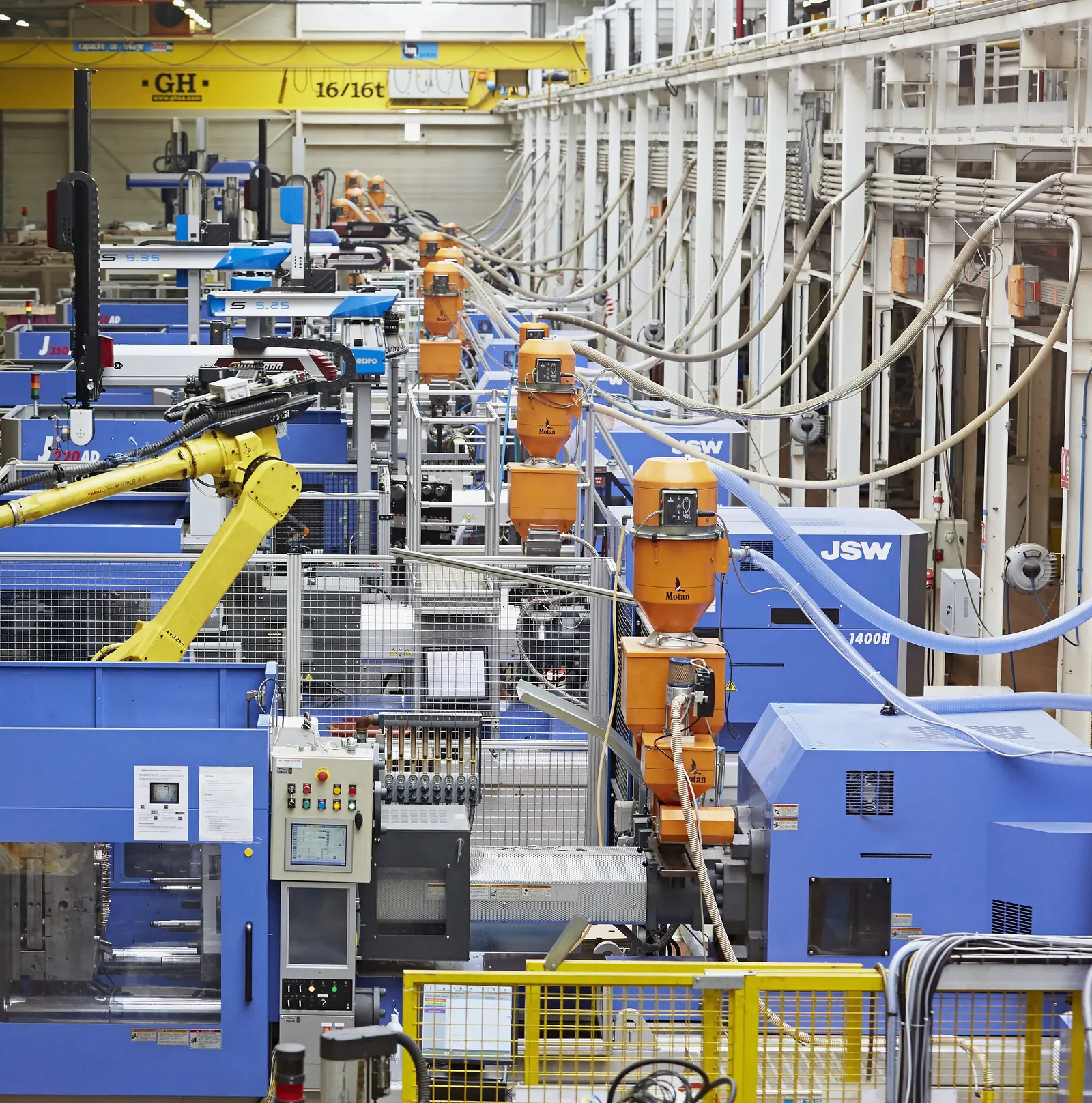 Rangée de presses à injecter équipées de robots de manipulation, Plazur Industries.